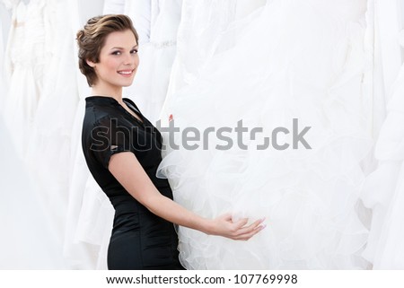 Shop assistant  is looking for the particular dress for the bride