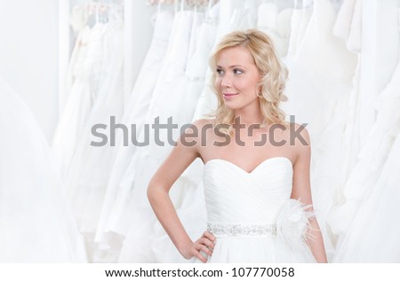 Young girl is trying a beautiful wedding gown on, white background