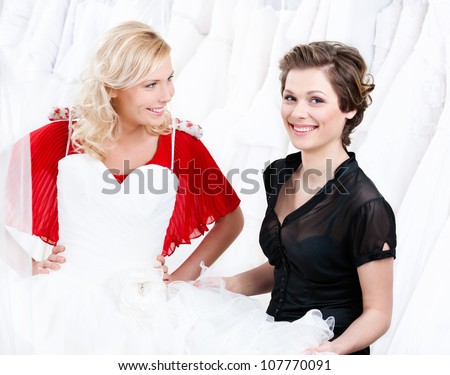 Hesitating about the wedding gown.Shop assistant persuades her