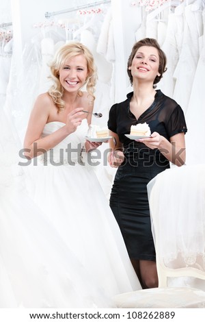 Laughing shop assistant and the bride eat a delicious cake celebrating a good decision