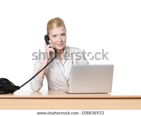 Young business woman sitting at a office table and holding phone handset, isolated