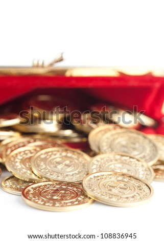 Scattered silver and gold coins are in  hot red purse, isolated on white. A great number of coins symbolize wealth, richness, income and profit. Close up shot.