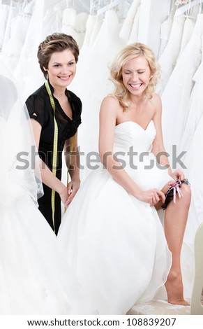Laughing future bride in wedding gown puts the garter