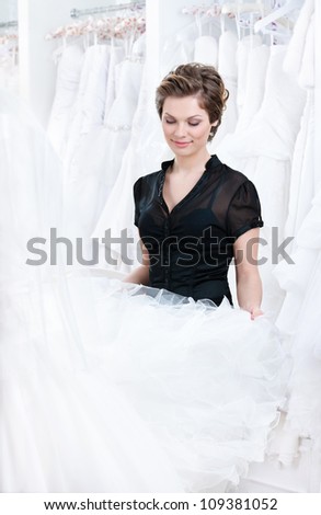Shop assistant wants to select a proper dress for the client, on white background.