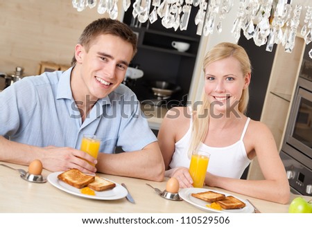 Smiley couple have light breakfast in the kitchen