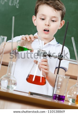 Little chemist pours colored liquid in conical flask holding an experiment