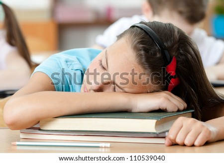 Tired schoolgirl sleeps at the desk, close up