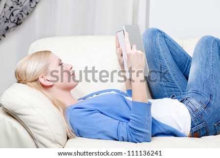 Pretty woman reads the book lying on the white leather sofa