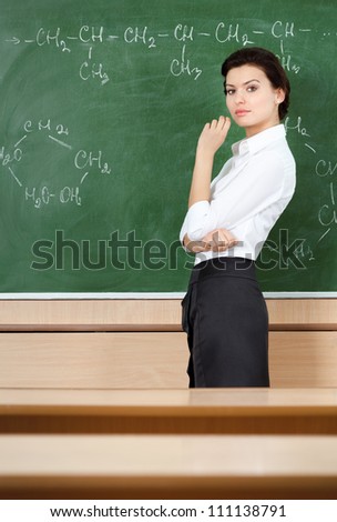 Serious teacher wrote chemical formula at the blackboard