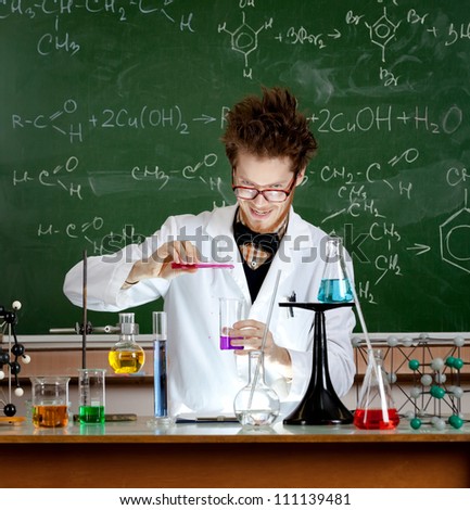 Mad professor pours some red liquid in beaker while making an experiment in his laboratory