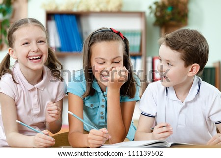 Laughing pupils help to each other to do the task