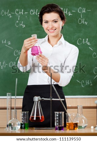 Smiley chemistry teacher holds a conical flask with purple liquid
