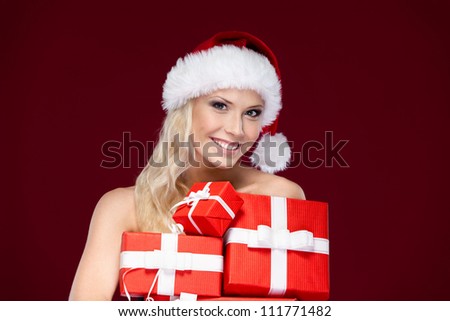 Beautiful lady in Christmas cap holds a set of gifts wrapped with red paper, isolated on purple