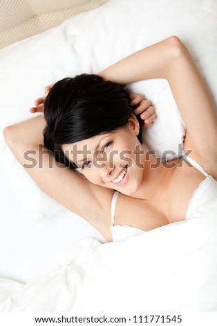 Sleeping woman in the bed with white bed linen, white background