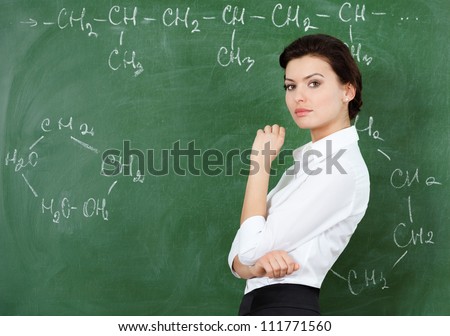 Smiley teacher at the chalkboard writes a chemical formula