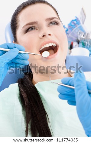 Dentist examines the mouth of the patient on the dentist\'s chair with the help of dental mirror