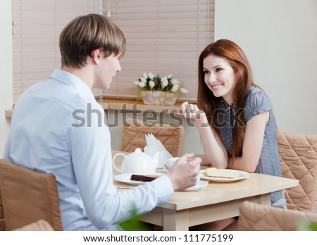 Woman talks with man sitting at the table at the coffee house