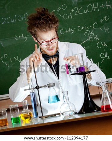 Mad professor gestures forefinger while conducting an experiment in his laboratory