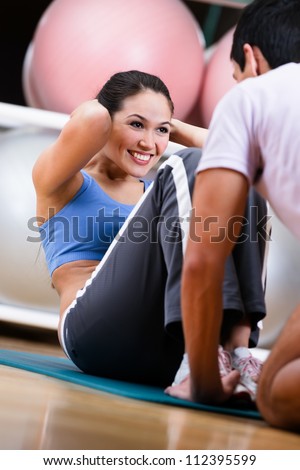 Woman does situps with coach in training gym