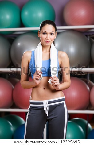 Athletic woman with perfect figure in fitness gym with shelves of gym balls