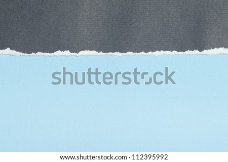 Grey textured paper with torn edge on blue background