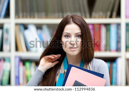 Female student with books at the library. Research. Information