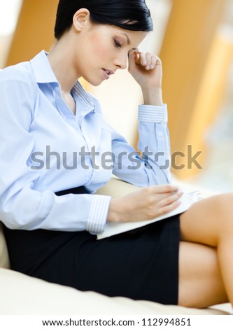 Business woman rests at the sofa reading book at the hall