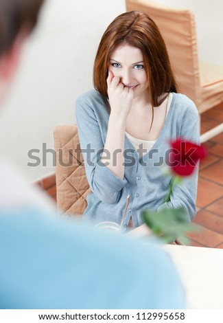 Man presents a red rose to his girlfriend at the coffee house