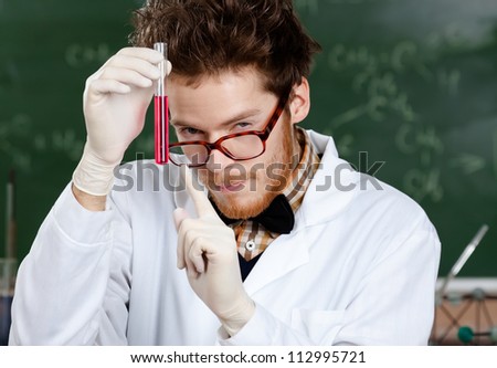 Mad professor points at the vial with colored liquid