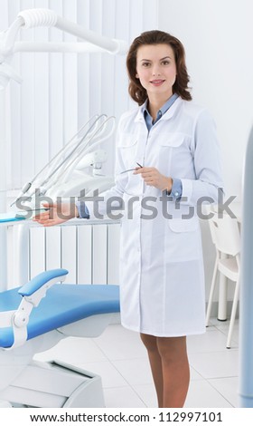 Beautiful doctor\'s assistant shows the dentist\'s chair