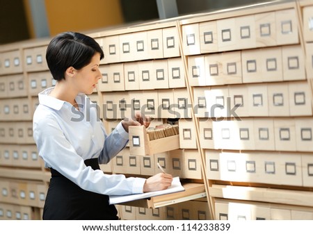 Woman searches something in card catalog composed of set of wood boxes at the library. Education