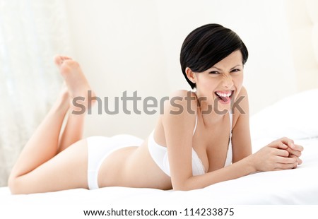 Woman in underwear is lying in the bed with white bedclothes, white background