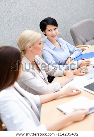 Female colleagues discuss business plan sitting at the meeting hall. Teamwork concept