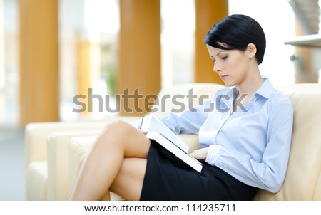 Business lady rests at the sofa reading book at the hall