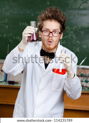Mad scientist shows two flasks with colored liquid in his laboratory