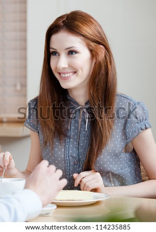 Woman talks with someone sitting at the table at the cafeteria