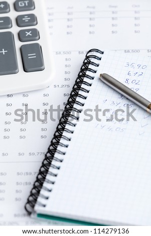 Close up of business stationery: writing pad, pen, calculator and some documents