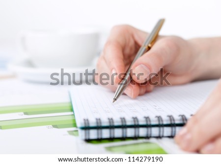 Close up of hand making notes in the writing pad lying on the diagrams