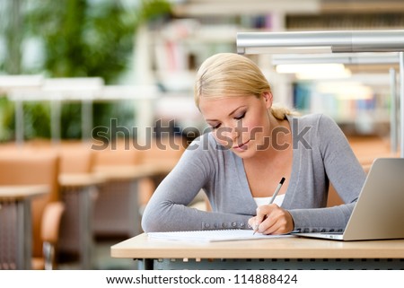 Female student working on the laptop sitting at the table. Process of learning