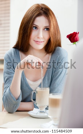 Woman with crimson rose sitting at the cafe