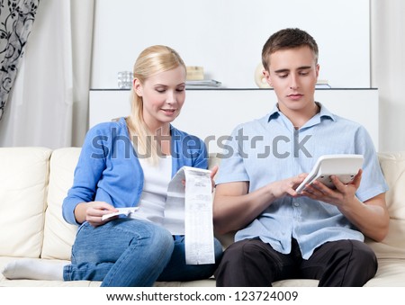 Married couple calculates the expenses sitting on the sofa