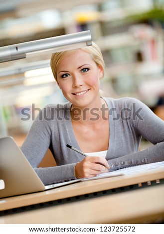 Female student working on the silver laptop sitting at the desk. Process of studying