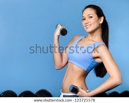 Sportswoman works out with dumbbells in gym Sportswoman works out with dumbbells in gym