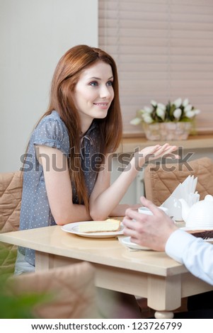 Woman talks with man sitting at the table at the cafe