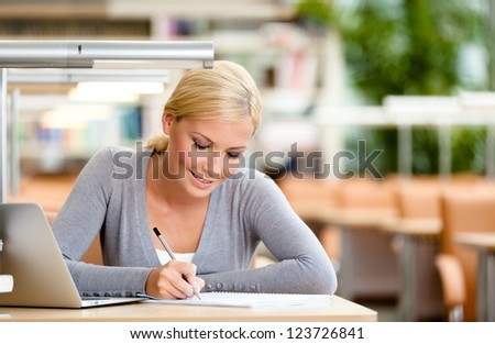 Female student studying on the laptop sitting at the desk. Process of studying