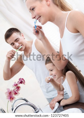 Family of three people brush their teeth in bathroom
