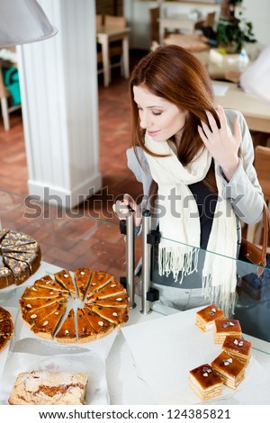 Woman in scarf looking at the bakery glass case full of different pieces of pies