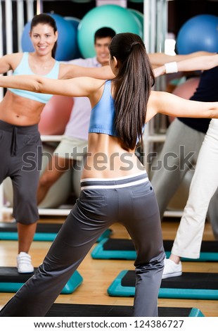 Sexy coach exercises with her group at the gym in a body shaping class