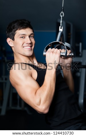 Athletic young man works out on gym equipment in fitness gym