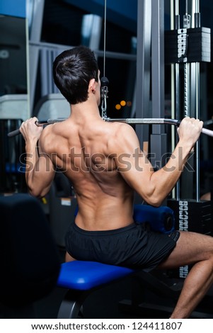 Athletic young man works out on simulator in fitness gym